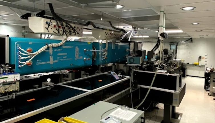 Equipment in a laser facility, including a blue enclosure and cables running down from the ceiling
