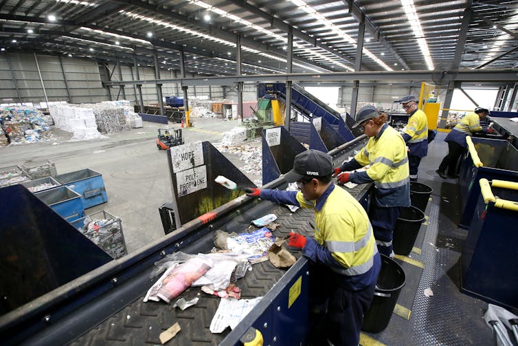 Workers manually sort waste from domestic recyclables