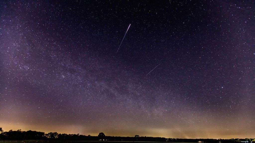 starry night scene with a long meteor trail - a lyrid high in the center of the image.