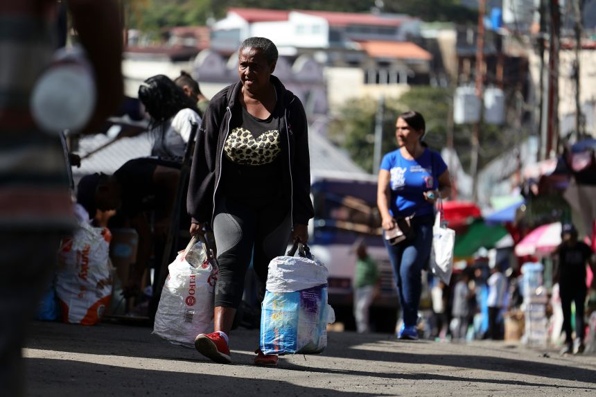A person walks with bags while shopping at a street market at the Petare neighborhood after the capture of Nicolas Maduro by US forces on January 8, 2026 in Caracas, Venezuela.