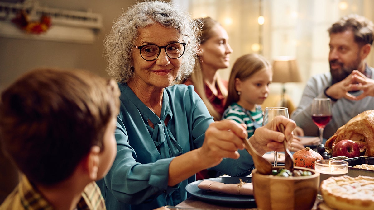 Smiling grandmother talking to her grandson during family dinner on Thanksgiving