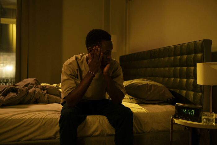 Man sitting on bed at night looking stressed, illustrating challenges healthcare workers never reveal to loved ones.