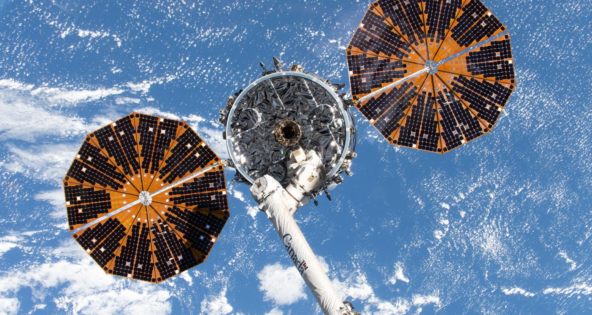 Northrop Grumman's Cygnus XL cargo spacecraft, with its two prominent cymbal-shaped UltraFlex solar arrays, is in the grasp of the Canadarm2 robotic arm before being released and departing the International Space Station to complete its resupply mission.