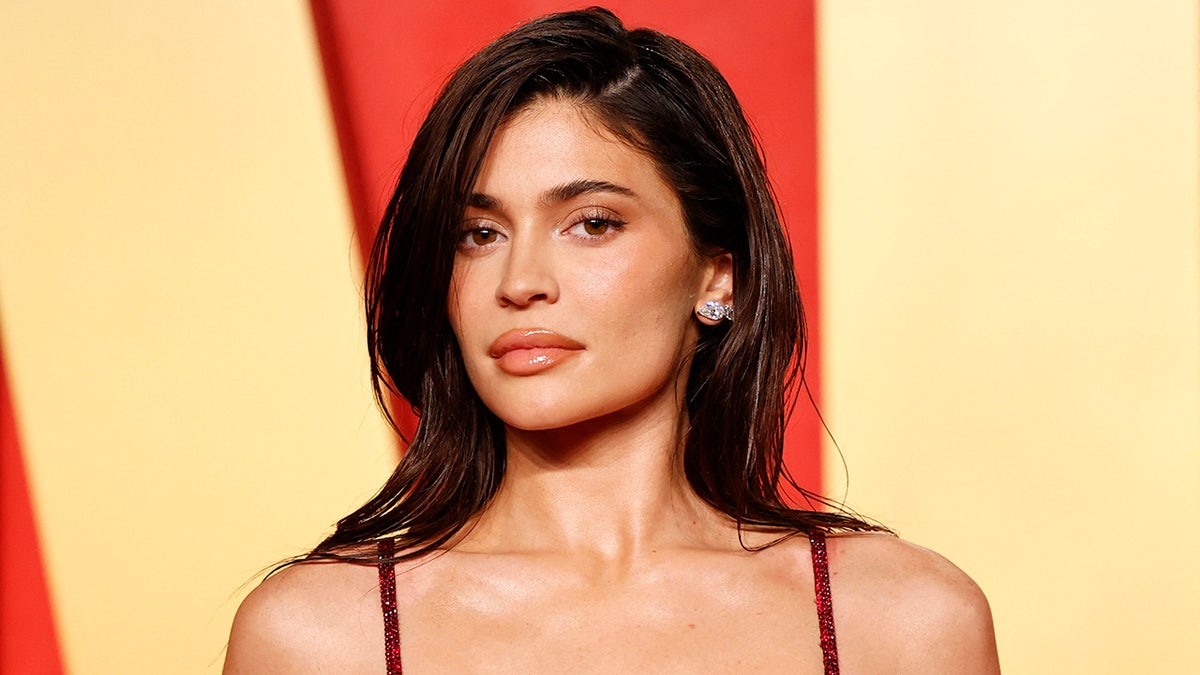 Kylie Jenner wearing a red strap dress looking directly at the camera at the Vanity Fair Oscar party