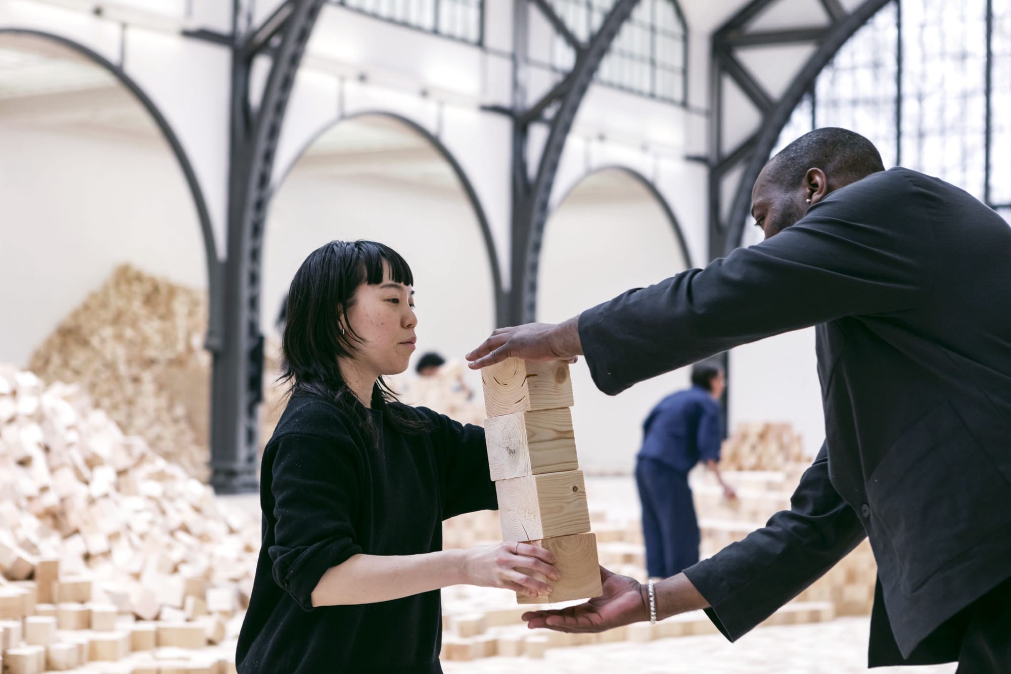 people work on an installation of wooden blocks by Lina Lapelytė in a cavernous building