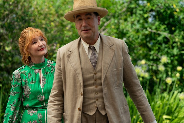 Lesley Manville as Susan Ryeland and Tim McMullan as. Atticus Pünd in Marble Hall Murders, walking with greenery in the background.