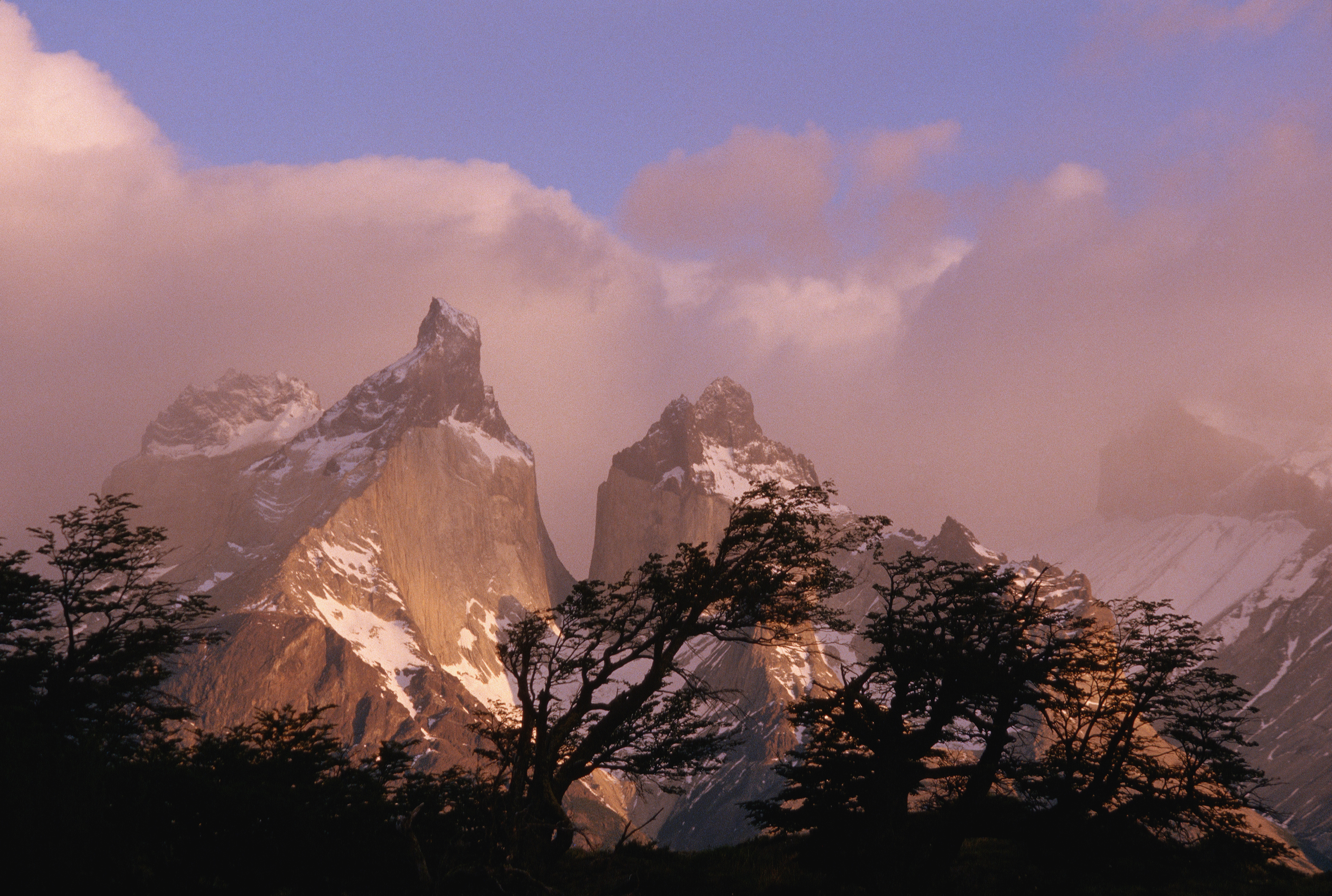 A layer of mist covers the mountain peaks of the Towers of Paine National Park at sunset. Paine National Park, Chile. (Photo by Galen Rowell/Corbis via Getty Images)
