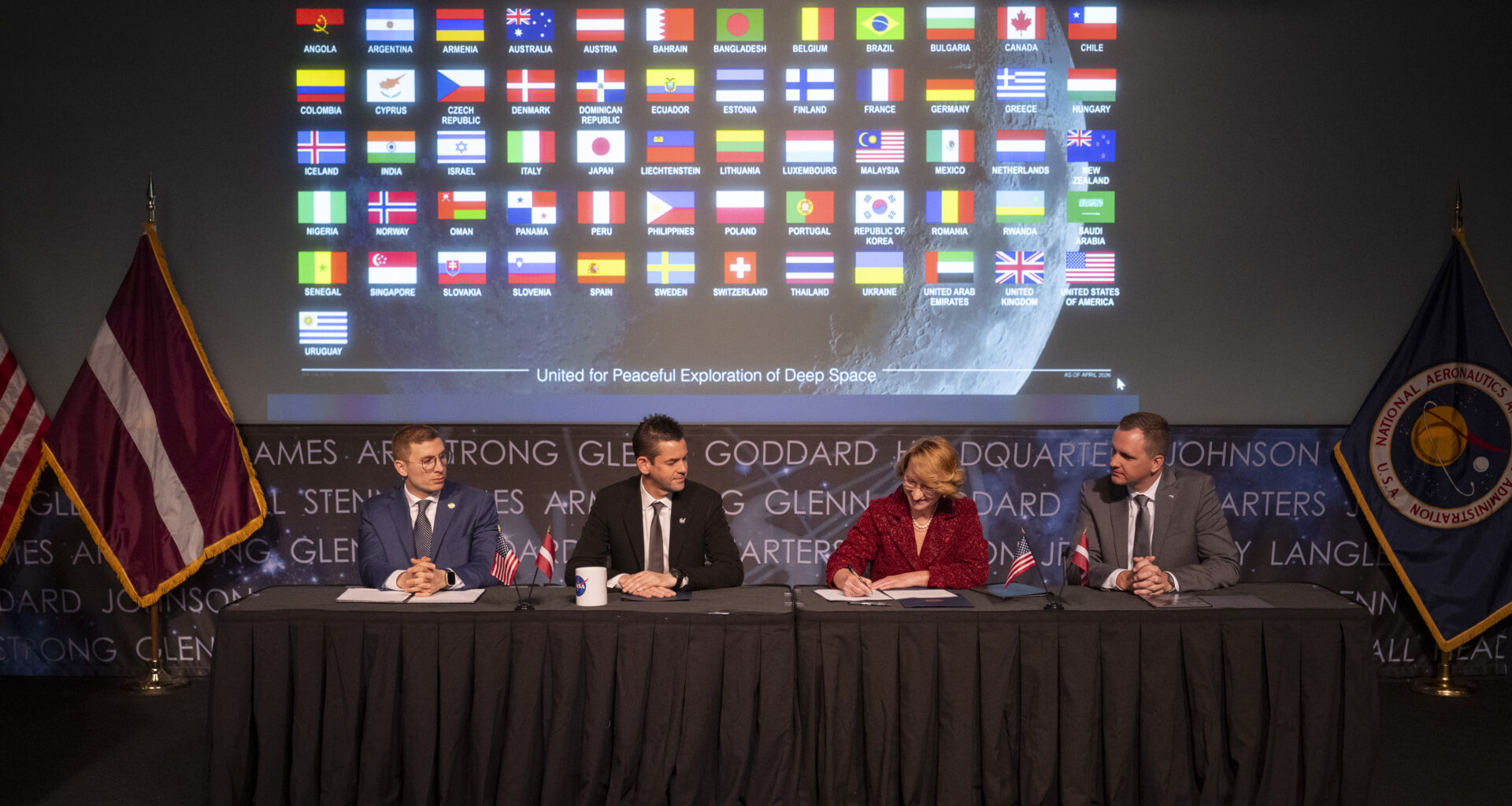 Dace Melbārde, Latvia’s Minister for Education and Science, second from right, signs the Artemis Accords, as NASA Administrator Jared Isaacman, second from left, Jacob Helberg, U.S. Under Secretary of State for Economic Affairs, left, and Jānis Beķeris, Chargé D’Affaires a.i. at the Embassy of the Republic of Latvia to the United States, right, look on Monday, April 20, 2026, at the Mary W. Jackson NASA Headquarters building in Washington. The Artemis Accords graphic of all signatory flags is behind them.