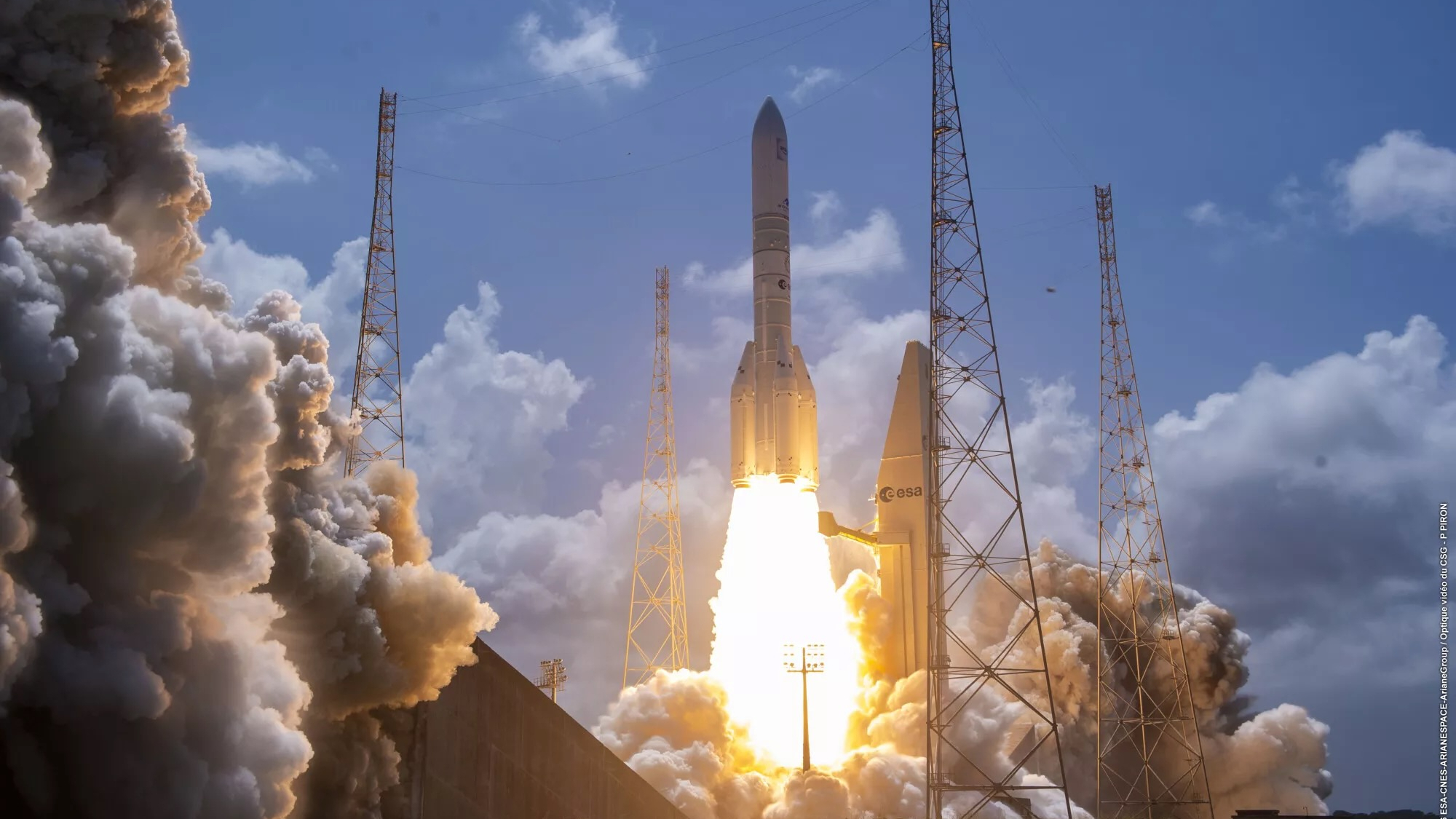 a big white rocket launches into a blue sky