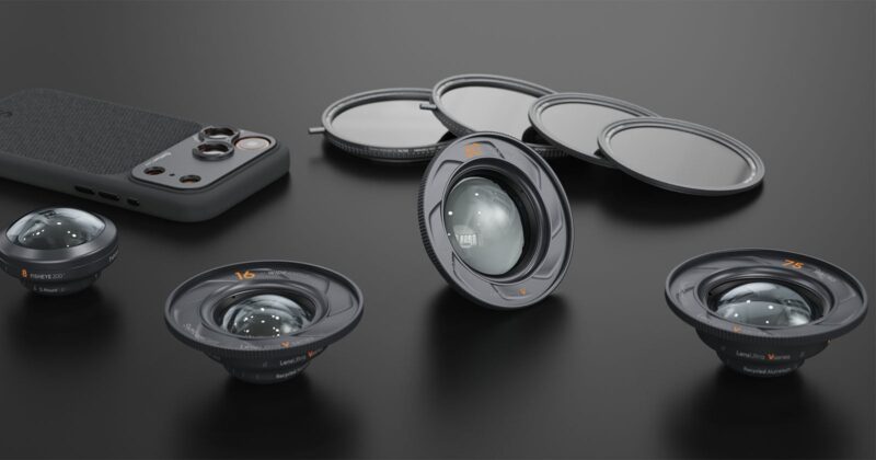Four camera lenses, three round lens filters, and a smartphone with a textured back are arranged on a dark surface, showcasing photography accessories in a neat layout.