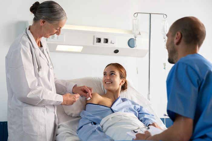 Surgical staff attending a smiling patient in hospital bed, discussing unhinged things patients confessed under sedation
