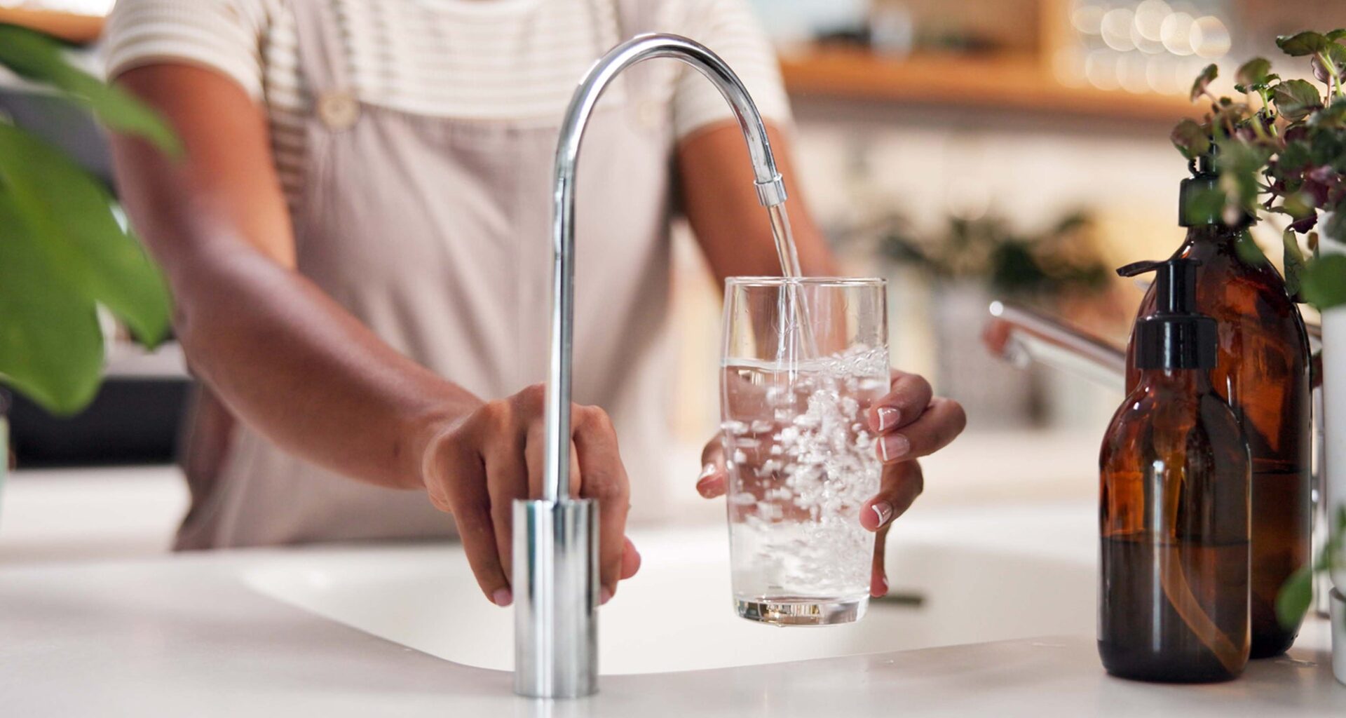 Person pouring water from a faucet into a glass