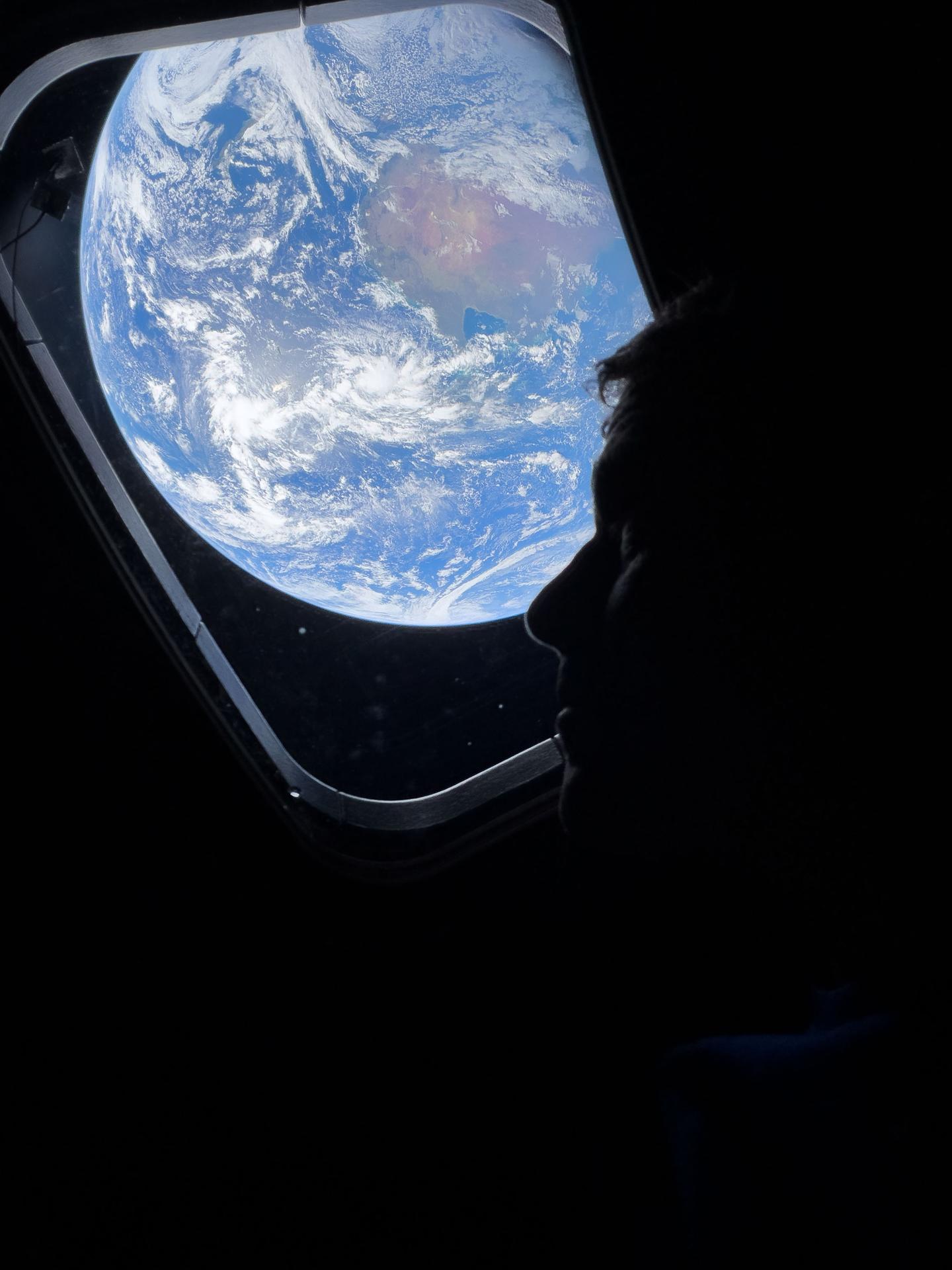 A photo from Artemis II: NASA astronaut and Artemis II Commander Reid Wiseman peers out of one of the Orion spacecraft's main cabin windows, looking back at Earth, as the crew travels towards the Moon.