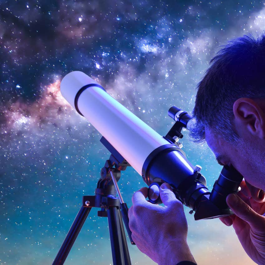 man looking through telescope at the night sky imagining color of universe