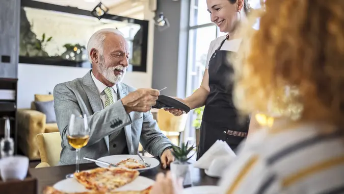 Father having pizza with daughter in restaurant ,paying bill stock photo