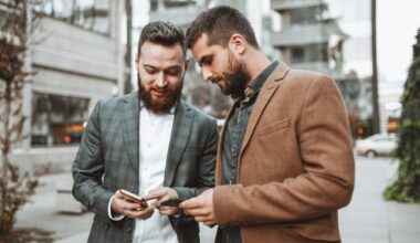 Two investors look at something on a smartphone while outdoors.