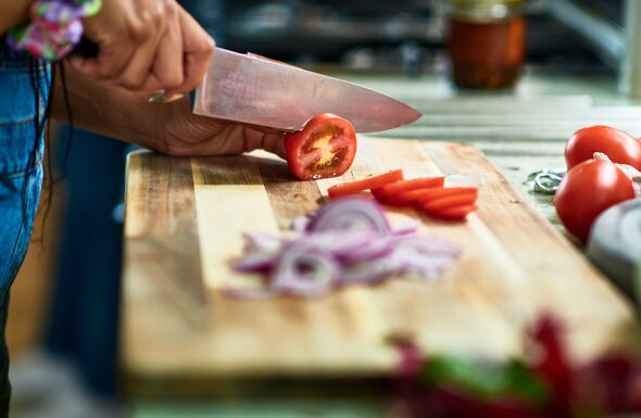 Woman chopping tomatoes on wooden board Woman chopping tomatoes on wooden board