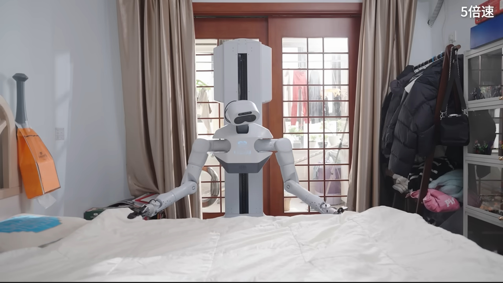 A white humanoid robot pulls the sheets across a bed