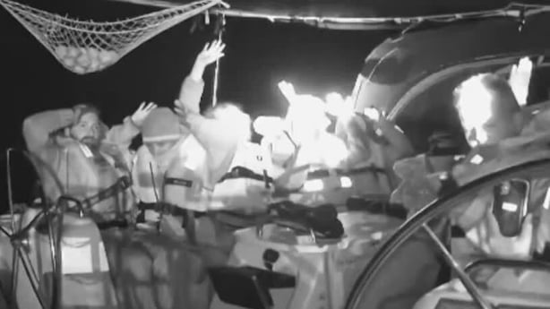 a black and white image shows people on board a board with their hands in the air
