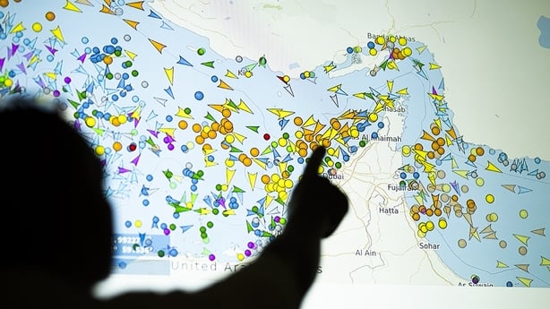 A person in front of a large screen displaying vessel movements in the Strait of Hormuz on a ship-tracking website.
