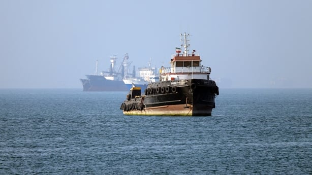 An Iran-flagged tugboat sails near a ship anchored in the Strait of Hormuz