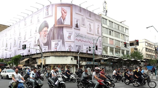 Iranians drive past a huge billboard carrying the image of the late Iranian supreme leader Ayatollah Ali Khamenei.