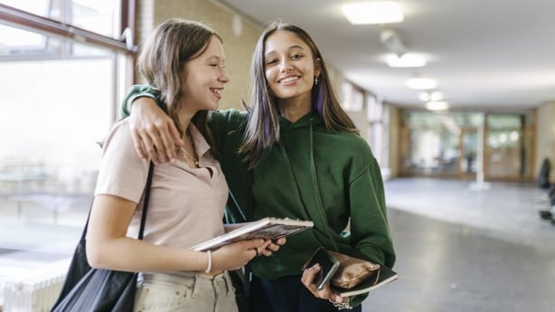 Two High School students hugging each other while on their way to their next class.