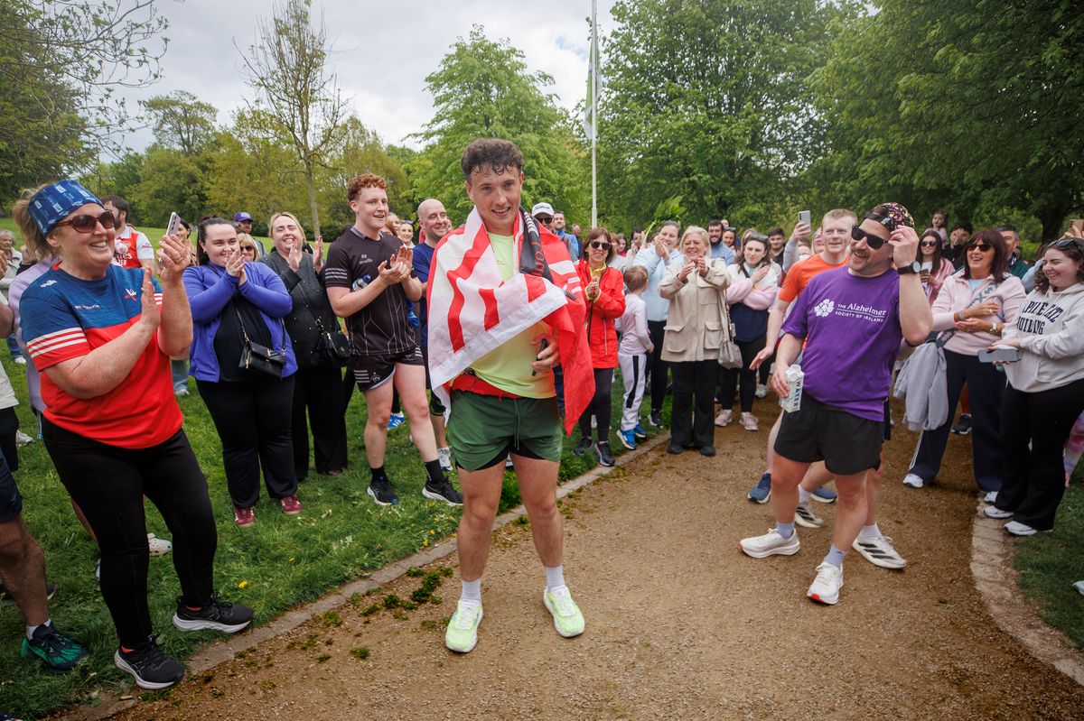 Jordan Adams (centre) from Redditch drapes a County Louth flag over his shoulders at Ice House Hill Park, Dundalk, County Louth, after completing his day eight marathon of a 32-day fundraising run in Ireland. 