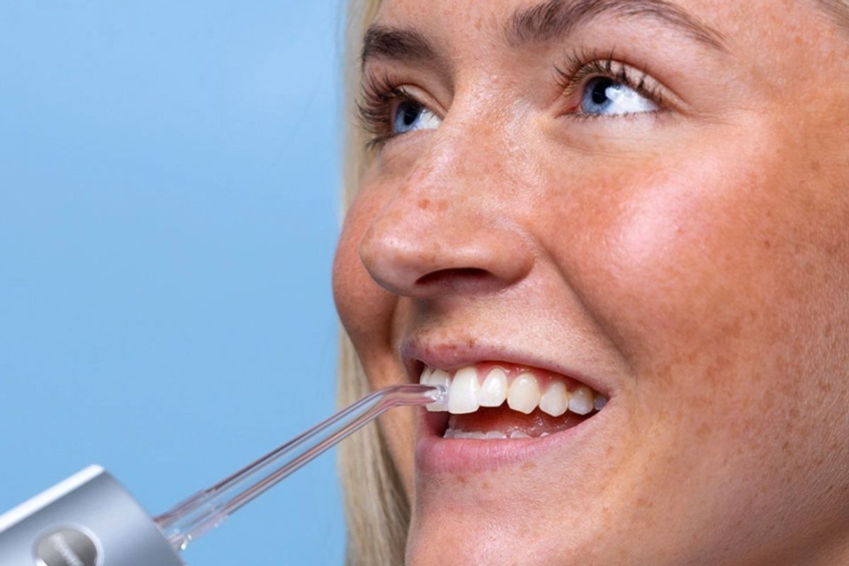 Close up of a woman using a water flosser on her teeth