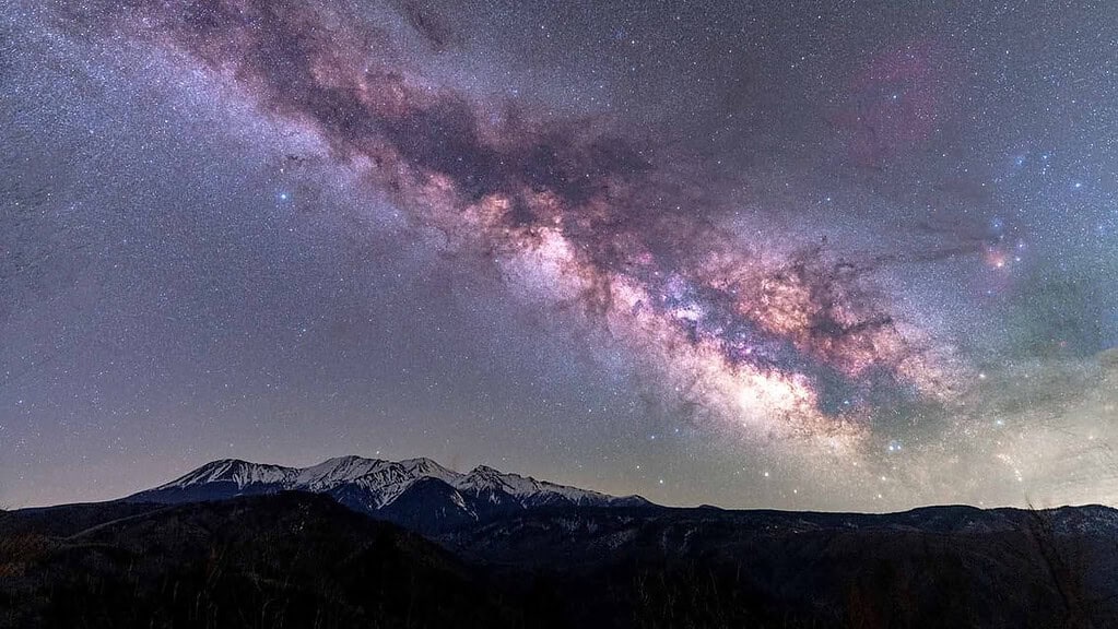 Milky Way galaxy visible above mountain landscape at night.
