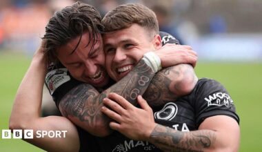 Carlisle defender Aaron Hayden has his hands covering his face while Boreham Wood player Cameron Coxe has his raised aloft in joy