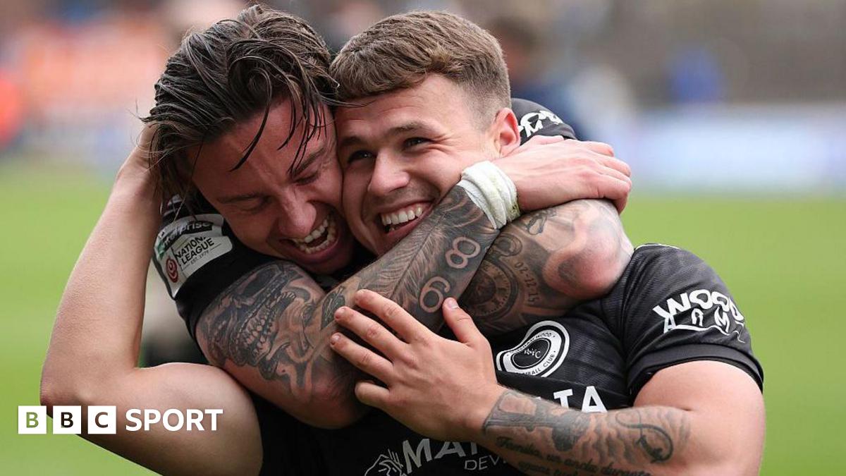 Carlisle defender Aaron Hayden has his hands covering his face while Boreham Wood player Cameron Coxe has his raised aloft in joy