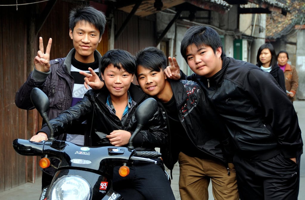 Four young high school students on their way home after class in China flash the peace sign for the camera. Photo: Shutterstock