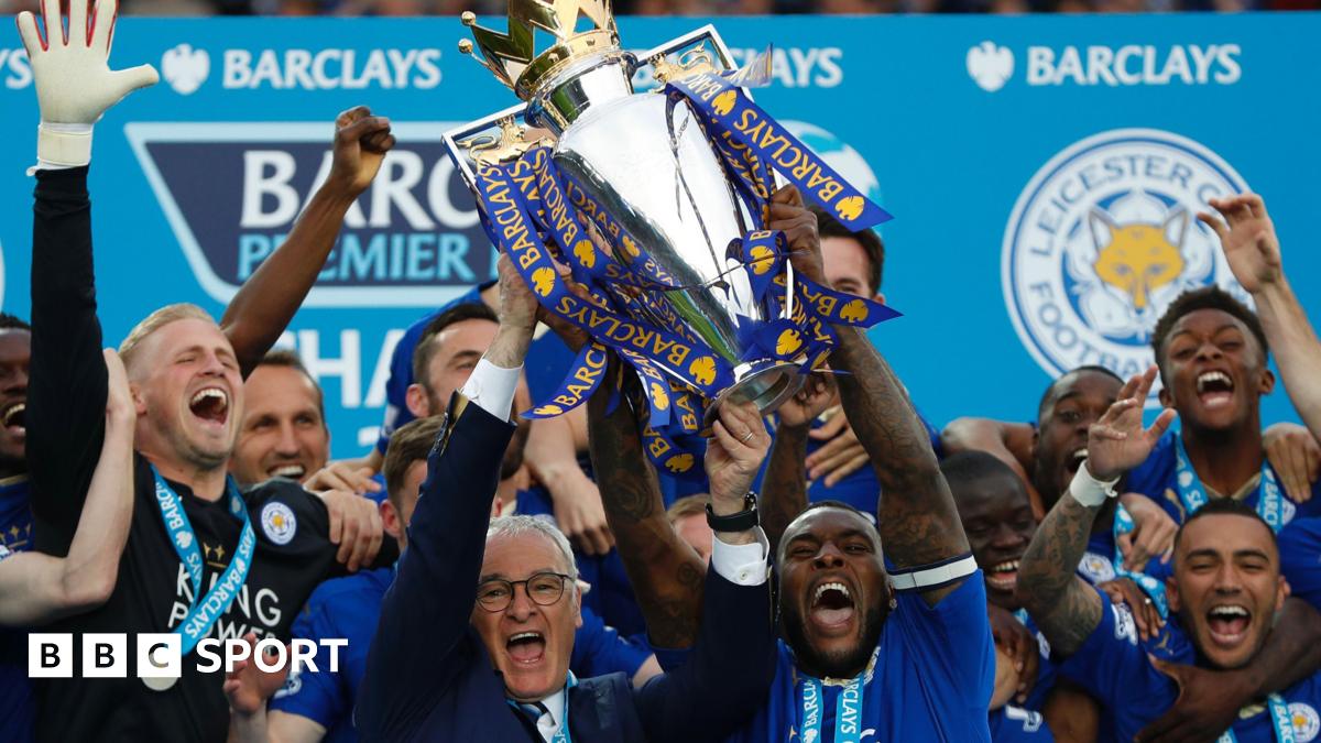 Leicester City manager Claudio Ranieri and captain Wes Morgan lift the Premier League trophy while surrounded by euphoric Foxes players