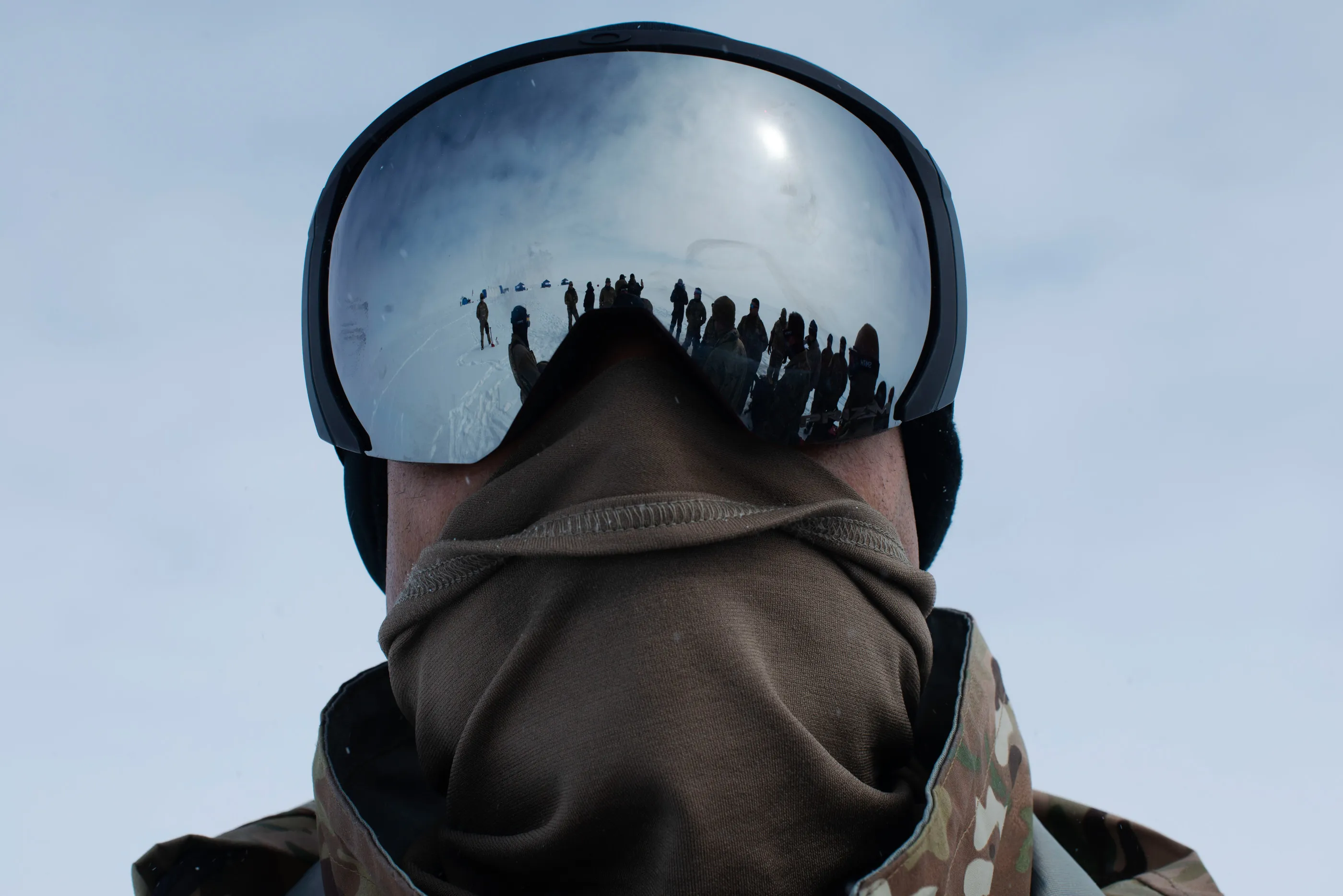 US military solidars undergoing Barren Land Arctic Survival Trainin are reflected in Master Sergeant Poitier Wright’s snow goggles.