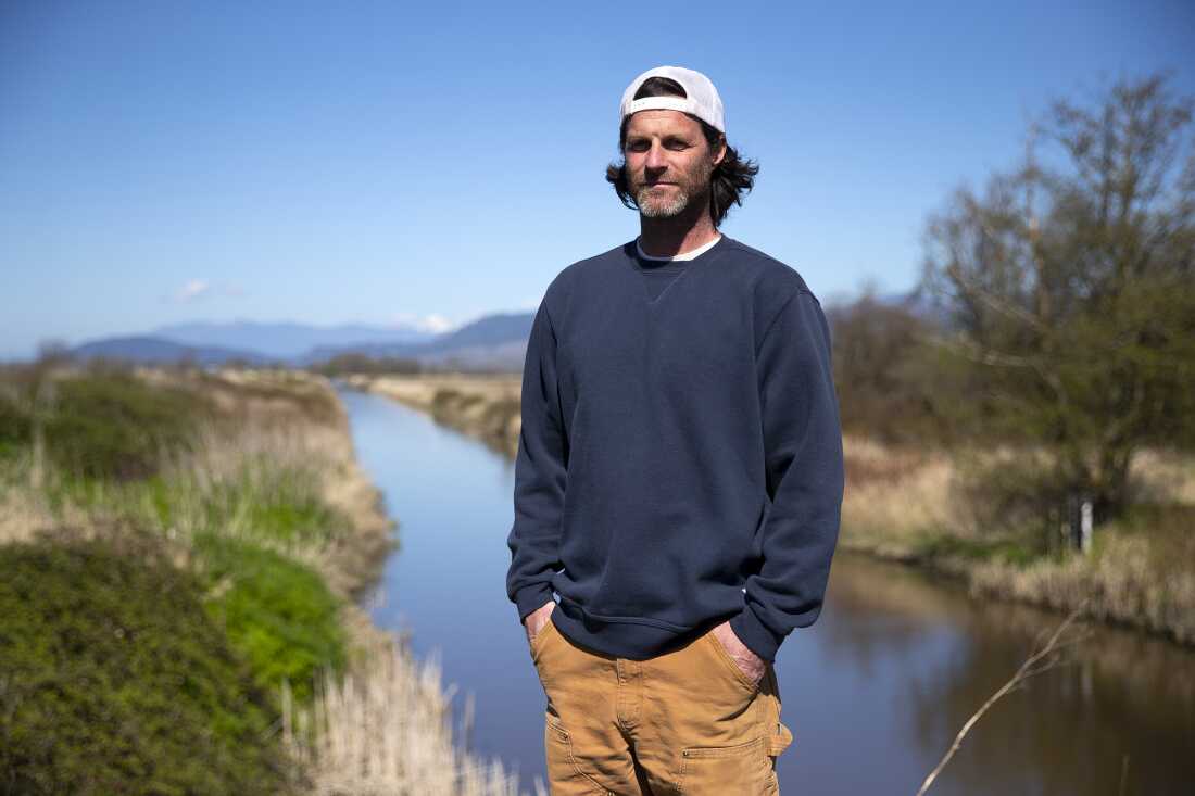 Fifth-generation farmer Tyler Breum stands along the Tom Moore Slough levee, near Big Ditch, close to his family’s farmland on April 8, 2026, near Stanwood, Wash.