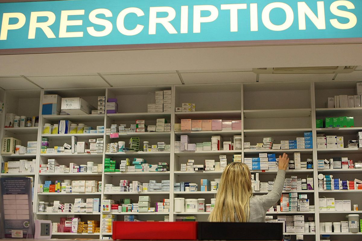 A member of staff stocks a pharmacy shelf