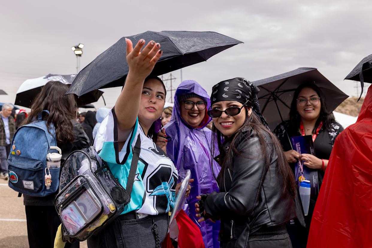 BTS fans shield themselves from light rain while waiting outside the Sun Bowl in El Paso, Texas, on Saturday, May 2, 2026, ahead of the first concert.