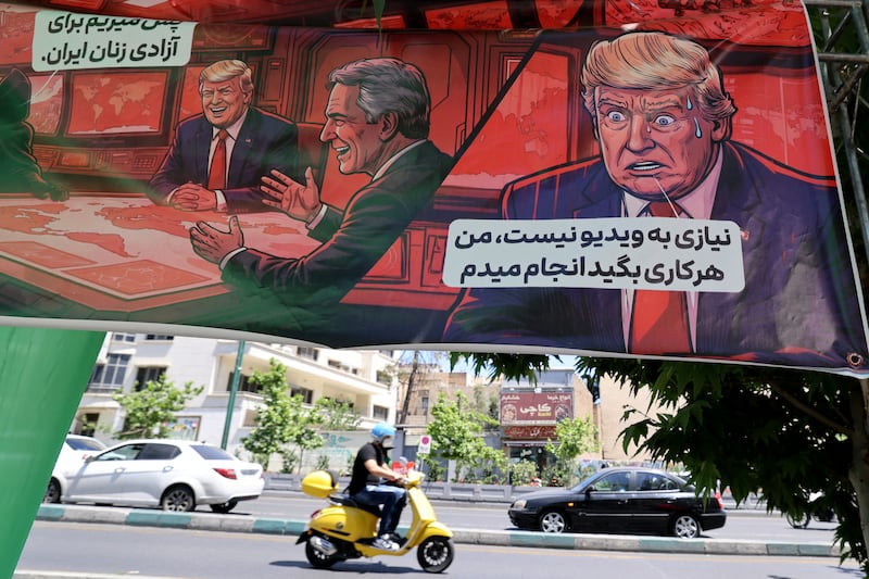 An Iranian man rides his moped past a banner depicting a cartoon of US president Donald Trump which reads in Tehran on Saturday. Photograph: Atta Kenare/AFP via Getty