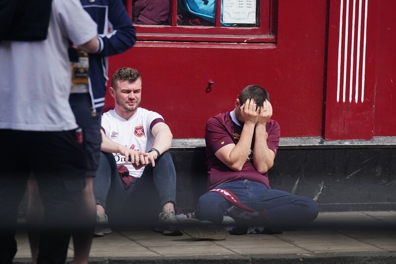 HEARTBREAK: Heart of Midlothian fans sit dejected outside a bar in Edinburgh showing the Scottish Premier League championship decider against Celtic. Pic: Jane Barlow/PA Wire.