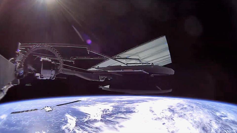 photo showing part of a satellite with earth in the background, and another satellite flying below