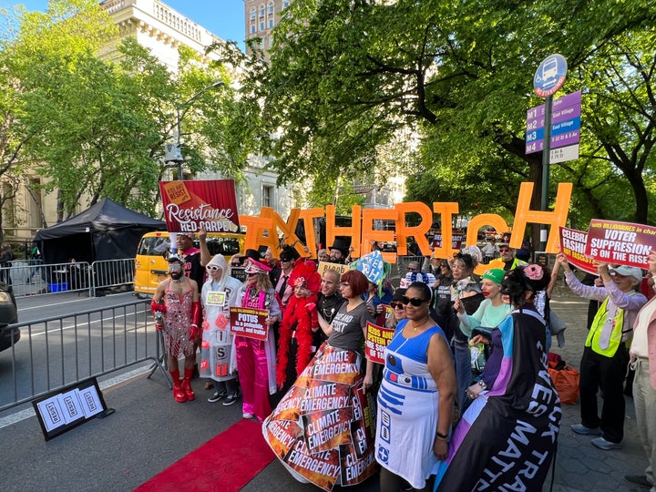 Protesters pose on a pop-up red carpet and hold up letters to read "TAX THE RICH" outside the Met Gala on Monday.
