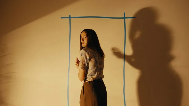 Renate Reinsve as Mary in front of a door made of tape in Backrooms
