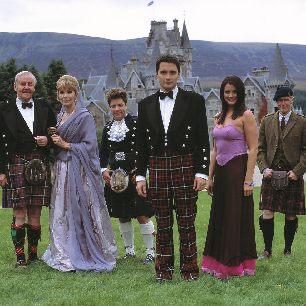 group of individuals dressed in formal scottish attire in front of a castle