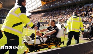 Xavi Simons being wheeled down a touchline on a stretcher