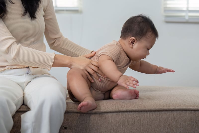 Mother helping baby sit up