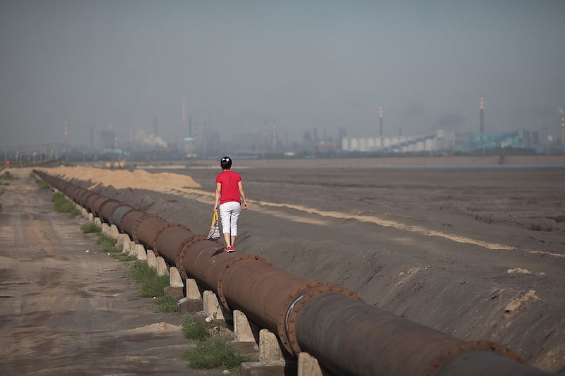 A woman standing on the banks of a 'toxic lake' surrounded by rare earth refineries near the inner Mongolian city of Baotou. Photograph: Ed Jones/AFP via Getty Images