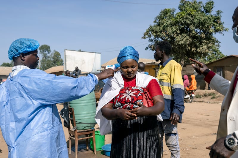 A health worker takes the temperature of a woman at a checkpoint in Bunia, Democratic Republic of the Congo. The outbreak is concentrated in Ituri, the war-torn province of which Bunia is the capital. Photograph: Arlette Bashizi/The New York Times
                      