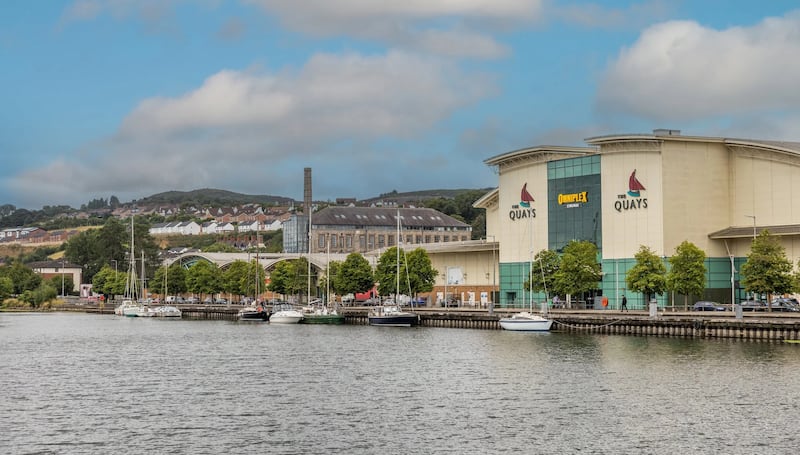 Wide image of The Quays Shopping Centre in Newry from a distance, with Newry's Canal in the foreground.