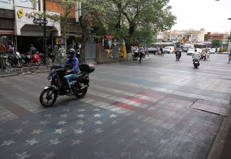 Iranians drive over a painting depicting the US and Israeli flags on a street in Tehran on Sunday. Photograph: Abedin Taherkenareh/EPA